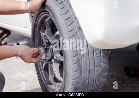 Händen der Mechaniker die Mutter des Autorades holen und anziehen Stockfoto