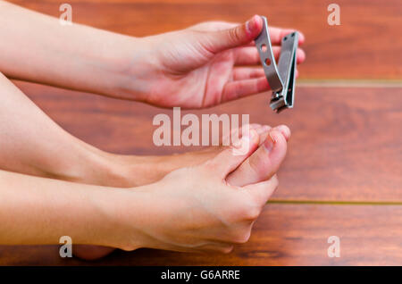 Mit Händen Metall Clipper schneiden Füße Nägel, hölzernen Hintergrund Stockfoto