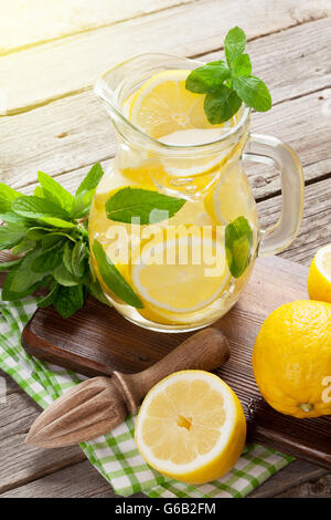 Limonade Krug mit Zitrone, Minze und Eis am Gartentisch Stockfoto