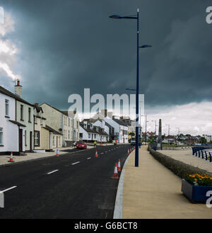 Donaghadee, County Down, UK 24. Juni 2016 Baustellen Verkehr Kegel verhindern Parkplatz mit dunklen grüblerischen Himmel über Reparaturen von Fahrbahnoberflächen als Teil der öffentlichen Investitionen Jeffrey Silber/Alamy Live News Stockfoto