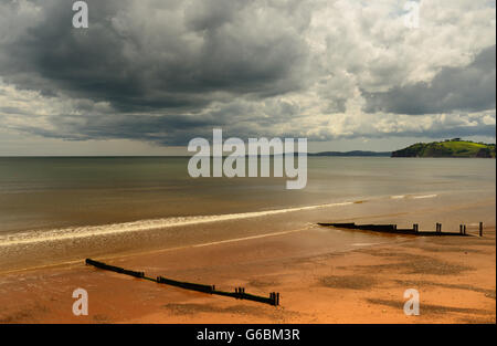 Regenwolken über eine ruhige See und einsamen Strand. Stockfoto