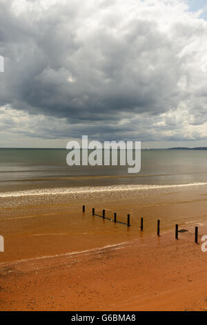 Regenwolken über eine ruhige See und einsamen Strand. Stockfoto