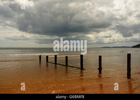 Regenwolken über eine ruhige See und einsamen Strand. Stockfoto