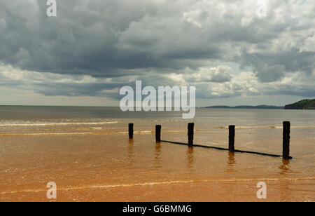 Regenwolken über eine ruhige See und einsamen Strand. Stockfoto