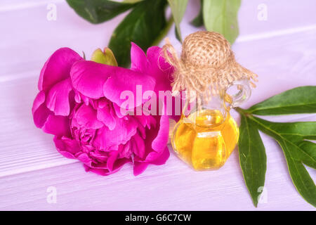 Wesentlichen Pfingstrose Öl und Blumen auf rosa Hintergrund aus Holz Stockfoto