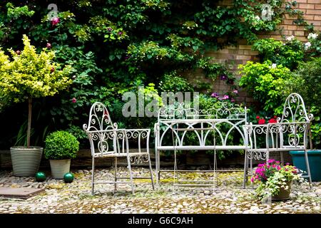 Al Fresco weiße schmiedeeiserne würfeln Tisch und Stühle in einem Innenhof Stockfoto