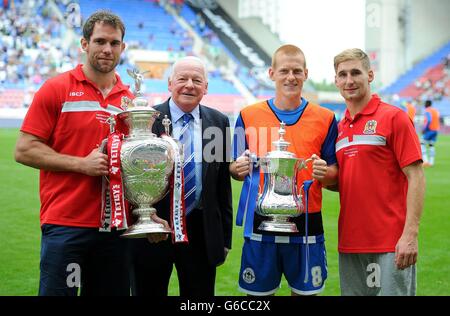 Ben Wigan Watson von Wigan Athletic (2. Rechts) hält den FA Cup mit Pat Richards, Rugby League-Spieler der Wigan Warriors (links), hält den Challenge Cup mit Dave Whelan (2. Links) und Wigan Warriors Sam Tomkins (rechts) während des Sky Bet Football League Championship-Spiels im DW Stadium, Wigan. Stockfoto