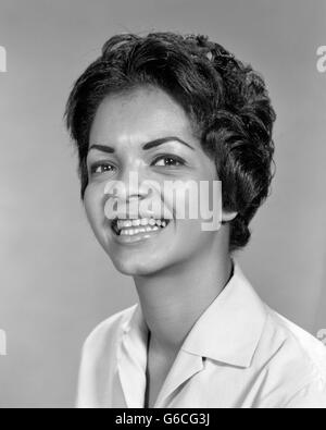 1960ER JAHRE PORTRAIT LÄCHELND AFROAMERIKANISCHE FRAU BLICK IN DIE KAMERA Stockfoto