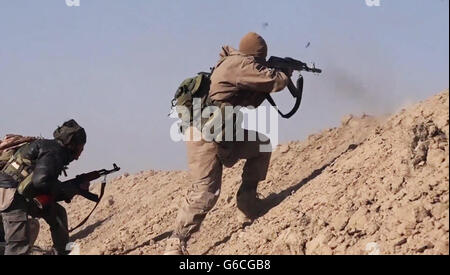 Islamischer Staat Kämpfer Feuer AK-47 Gewehre bei kämpfen in den Bergen Makhoul 30. Mai 2016 in der Nähe von Baiji, Irak. Das Standbild wird aus einem Propaganda video veröffentlicht von der islamischen Staates im Irak und der Levante erfasst. Stockfoto