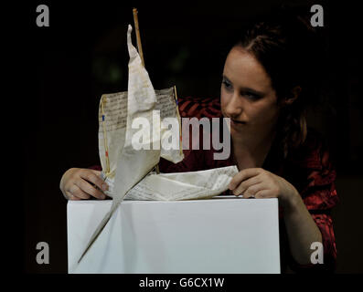 Gallery Assistant Polly Millner, passt Pageant Boat an, das aus einem alten, auf Velum geschriebenen Willen des Künstlers Edmund Prizeman, 16, hergestellt wurde, da mehr als fünfzig Kunstwerke, die vom Thames Diamond Jubilee River Pageant inspiriert wurden, in der Pump House Gallery, Battersea Park, London, kostenlos öffentlich ausgestellt werden. Im Rahmen des Mayor's Thames Festivals 2013 vom 4. Bis 15. September. Stockfoto