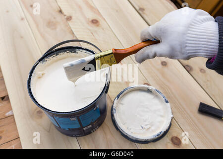 Malerei Holz Bretter außerhalb mit weißer Farbe oder weiß farbigen Emulsion mit 2 Zoll Pinsel malen. DIY-außen-Projekt Stockfoto