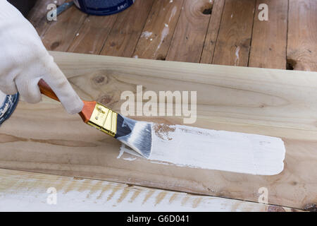 Malerei Holz Bretter außerhalb mit weißer Farbe oder weiß farbigen Emulsion mit 2 Zoll Pinsel malen. DIY-außen-Projekt Stockfoto