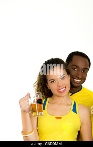 Charmantes interracial paar tragen gelbe Trikots, posiert für die Kamera hält Bierglas und lächelnd, weiße Studio-Hintergrund Stockfoto