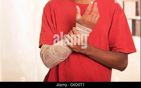 Closeup Mann im roten Hemd tragen große graue Binde über den rechten Unterarm mit der anderen Hand zu unterstützen Stockfoto