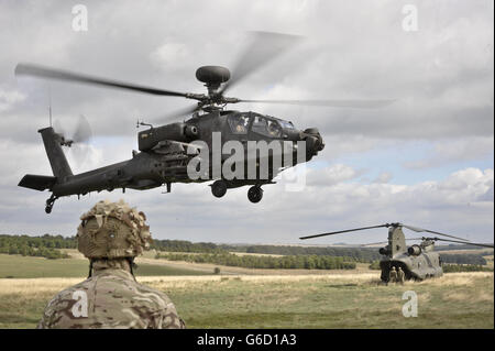 Ein Apache-Angriffshubschrauber landet hinter einem Chinook-Hubschrauber auf dem Militärtrainingsgelände von Wiltshire in der Salisbury Plain, als sich die 7. Panzerbrigade auf den Einsatz in Afghanistan bei der Operation HERRICK 19 vorbereitet. Stockfoto