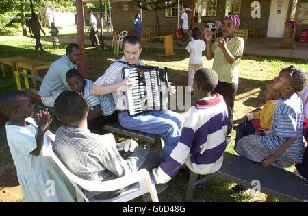 Pilot Simon Wood aus Barnett, London, wechselt seine Fluginstrumente in ein musikalisches, während er während einer Osterparty in einem Waisenhaus in Nairobi, Kenia, ein HIV-positives Waisenkind unterhält. Simon, der als Senior First Officer bei British Airways arbeitet, war einer von 20 Mitarbeitern der Fluggesellschaft, die im Nyumbani-Waisenhaus eine Osterparty für 79 Kleinkinder veranstalteten. Das in Nairobi ansässige Waisenhaus kümmert sich nur um HIV-positive Waisen, die entweder ihre Eltern an AIDS verloren haben oder allein zur Selbsthilfe und Bekämpfung der Krankheit verlassen wurden. Stockfoto