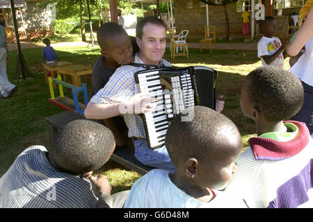 Pilot Simon Wood aus Barnett, London, wechselt seine Fluginstrumente in ein musikalisches, während er während einer Osterparty in einem Waisenhaus in Nairobi, Kenia, ein HIV-positives Waisenkind unterhält. Simon, der als Senior First Officer bei British Airways arbeitet, war einer von 20 Mitarbeitern der Fluggesellschaft, die im Nyumbani-Waisenhaus eine Osterparty für 79 Kleinkinder veranstalteten. Das in Nairobi ansässige Waisenhaus kümmert sich nur um HIV-positive Waisen, die entweder ihre Eltern an AIDS verloren haben oder allein zur Selbsthilfe und Bekämpfung der Krankheit verlassen wurden. Stockfoto