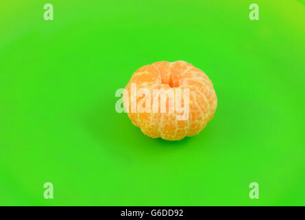 Geschälte Orange Clementine und Abschnitte über helle grüne Platte Stockfoto