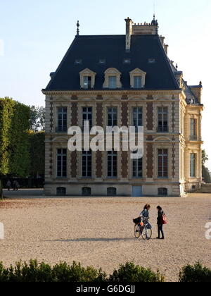 Zwei junge Damen, die miteinander reden, mit dem Schloss de Sceaux im Hintergrund. Stockfoto