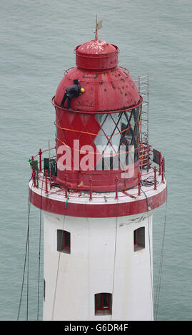 Ingenieure arbeiten an der Spitze des Beachy Head Lighthouse in der Nähe von Eastbourne, Sussex, während der Prozess der Neulackierung der Struktur nach einer erfolgreichen Spendenaktion zur Rettung der Streifen beginnt. Stockfoto