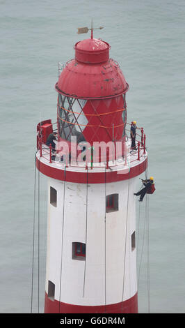 Ingenieure arbeiten an der Spitze des Beachy Head Lighthouse in der Nähe von Eastbourne, Sussex, während der Prozess der Neulackierung der Struktur nach einer erfolgreichen Spendenaktion zur Rettung der Streifen beginnt. Stockfoto