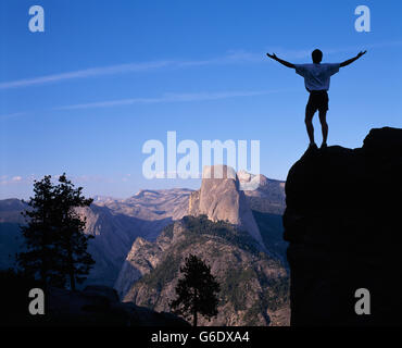 USA, California, Yosemite-Nationalpark, steht Wanderer auf Felsen mit Blick auf Half Dome, Yosemite-Tal bei Sonnenuntergang Stockfoto