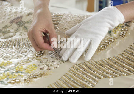 Das Krönungskleid der Königin aus weißem Satin wird für die Sommereröffnung der Buckingham Palace State Rooms von der leitenden Textilkonservatorin Janet Woods bei der Arbeit im Textile Conservation Studio im Hampton Court Palace in SW London vorbereitet. * Wenn das von Norman Hartnell entworfene und mit Stickereien aus Gold- und Silberfäden verzierte Kleid mit Samenperlen und Kristallen geschmückt ist, können die Besucher auch die erste öffentliche Schau des gesamten Krönungsfries von Feliks Topolski sehen. Stockfoto