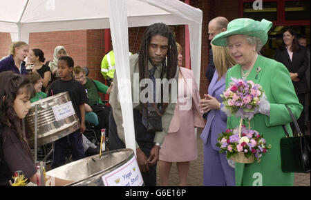 Die britische Königin Elizabeth II. Trifft den Musikdienstlehrer Hubert Placide bei einem Besuch der Mounstuart Primary School in Butetown, Cardiff. Stockfoto