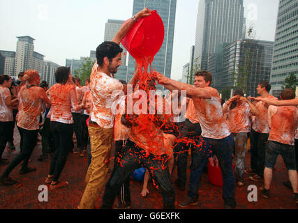 Menschen werfen Tomaten während Mission Deli Wraps Neugestaltung des berühmten spanischen Tomatenwerfen Festival, La Tomatina, in Canary Wharf, Central London. Stockfoto