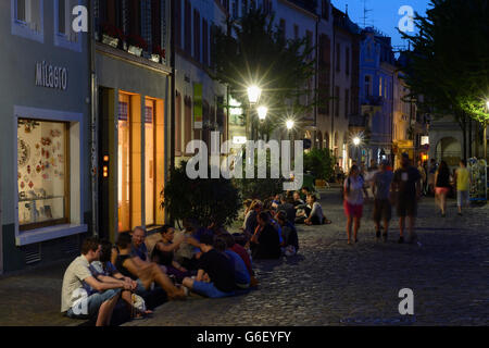 Studenten sprechen und trinken, sitzen auf einer Rinne (Bächle) im Quadrat dieses, Freiburg Im Breisgau, Deutschland, Baden-W Stockfoto