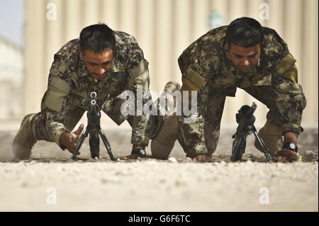 Die Soldaten der Afghan National Army (ANA) der 3. Brigade 209 Kandak tauchen zu ihren Waffen ein, während sie im ANA Camp Shorabak, Provinz Helmand, Afghanistan, von britischen und amerikanischen Soldaten in Schiesskunst ausgebildet werden. Stockfoto