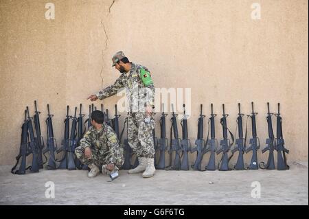 Soldaten der afghanischen Nationalarmee (ANA) stellen Waffen gegen eine Schlammmauer im ANA Camp Shorabak, Provinz Helmand, Afghanistan. Stockfoto