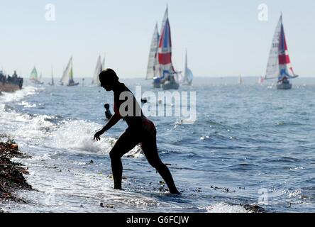 Am zweiten Tag der Skandia Cowes Week, der jährlichen Segelregatta auf der Isle of Wight, schlendern Frauen den Strand entlang. Es ist das größte Segelevent der Welt und dauert acht Tage mit über 950 Booten in 37 Klassen. Stockfoto