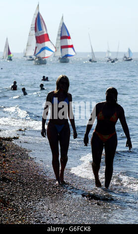 Zwei Frauen schlendern am Strand entlang in Cowes auf der Isle of Wight, am zweiten Tag der Skandia Cowes Week, der jährlichen Segelregatta auf der Isle of Wight. Es ist das größte Segelevent der Welt und dauert acht Tage mit über 950 Booten in 37 Klassen. Stockfoto