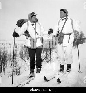 Die Schauspieler Richard Harris (links) und Kirk Douglas pflügen in Norwegen durch starken Schnee, während sie für den Kriegsfilm The Heroes of Telemark vor Ort sind. Stockfoto