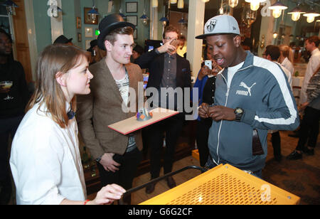 Die Gäste Oli White (Mitte) und der Gründer von SBTV Jamal Edwards (rechts) versuchen während der britischen Markteinführung des neuen aromatisierten Spirituosengetränks ODDKA im Brunswick House in Vauxhall, London, einen Becher an einer Experimentierstation zu machen. Stockfoto