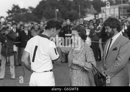 Prinz Charles küsst bei der Verleihung des Silver Jubilee Cup im Guards Polo Club, Windsor Great Park, die Hand seiner Mutter, Königin Elizabeth II., gnadenlos. Das Team des Prinzen, England II, schlug Brasilien, um den Pokal zu holen. Stockfoto