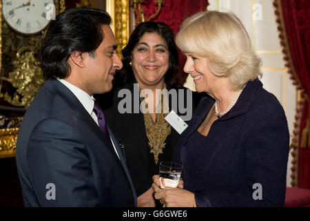 Die Herzogin von Cornwall trifft auf den britisch-indischen Komiker Sanjeev Bhaskar und den Filmregisseur Gurinder Chadha bei einem Empfang im Clarence House im Zentrum von London. Der Empfang war für Mitglieder der britischen indischen und srilankischen Gemeinden im Vorfeld der Reise des Prinzen von Wales und der Herzogin von Cornwall durch Indien und Sri Lanka im November. Stockfoto