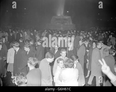 In Erwartung der Funken und der Raketen drängen sich Gruppen junger Menschen auf dem Trafalgar Square, einem traditionellen Zentrum der Guy Fawkes Night (5. November). * Trotz der extra Polizei war die Luft voll von den Geräuschen von Kalben und Gewittern und Raketen, die über den mit Fluten beleuchteten Brunnen rasten. Um zehn Uhr waren etwa 60 Menschen im Trafalgar Square verhaftet worden. In der nahe gelegenen Duncannon Street saß eine Gruppe von behelmten Polizisten ruhig in einem abgedunkelten Bus, bereit für Notfalleinsätze. Stockfoto