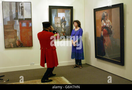 Der Chelsea-Rentner Bill Miles fotografiert die Künstlerin Louise Courtnell vor Gemälden des verstorbenen Plymouth-Künstlers Robert Lenkiewicz, während eine Sammlung seiner Gemälde von Sothebys Olympia in London versteigert wurde. Miss Courtnell, die bei Lenkiewicz studierte und vor kurzem ein Porträt des neuen Erzbischofs von Canterbury, Rowan Williams, von links, Selbstporträt am Fuß der Treppe, Wolfe Malerei an Staffelei und Maler mit Esther fertig gestellt hat. Stockfoto