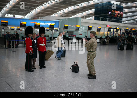Ein BA-Mitarbeiter mit Soldaten im Terminal 5 am Londoner Flughafen Heathrow, der sich am Londoner Poppy Day der Royal British Legion (RBL) den Mohnhändlern anschloss. Stockfoto