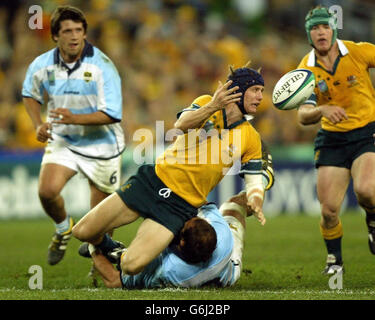 Der Australier Stephen Larkham hat sich beim australischen Sieg 24-8 im Eröffnungsspiel der Rugby-Weltmeisterschaft 2003 im Telstra Stadium in Sydney gegen den Argentinier Gonzalo Longo im Tackle abgesetzt. Stockfoto