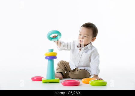 Kleine asiatische junge spielt mit Stapeln von bunten Ringe Spielzeug - Isolated on White Stockfoto