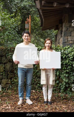 Junge asiatische Brautpaar Holding Blank Board im Wald Stockfoto