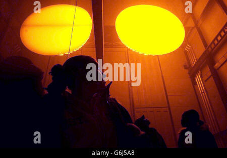 Die Besucher reichen nach oben, während sie unter Olafur Eliassons Installation 'The Weather Project' in der Tate Modern Gallery in London liegen. Seit der Eröffnung am Donnerstag haben mehr als 100,000 Menschen die neue Ausstellung des in Dänemark geborenen Künstlers besucht. Er hat eine verspiegelte Decke in einer riesigen Halle der Galerie installiert, die die Besucher dazu veranlasst, lange, nach oben starrende Zaubersprüche zu verweilen. Eliasson hat auch etwas installiert, das wie eine riesige gelbe Sonne aussieht und die Luft mit einem Nebel gefüllt, der Nebel oder Wolken ähnelt. Stockfoto