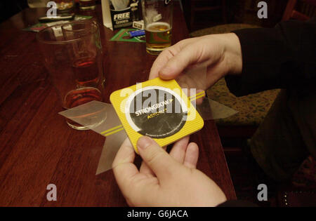 Ein Mitglied des Publikums kippt in einem Pub im Zentrum Londons einen 'AEROMAT', während das traditionelle Bierdeckel-Flipping etwas von einer Revolution durchläuft. Das neue Design, das von der Apfelmarke Strongbow in Auftrag gegeben wurde, sieht aus wie jede quadratische Tropfmatte, verwendet aber ein gewölbtes Stück Karton, zwei Drittel seiner Länge. Das Design gibt jedem Spieler, der Smash and Grab spielt - die Matte vom Rand eines Tisches hochklappen und mitten in der Luft fangen - einen zusätzlichen Vorteil. Die neuen Aeromats wurden an Studentenbars in London, Manchester und Nottingham geschickt. Stockfoto