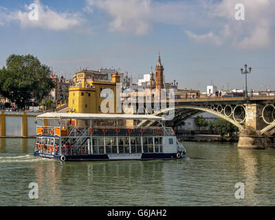 SEVILLA, SPANIEN - 15. MÄRZ 2016: Sightseeing-Boot auf dem Fluss Guadalquiver nähert sich der Triana-Brücke Stockfoto