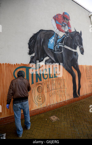 Der Graffiti-Künstler Olivier Roubieu wendet den letzten Schliff auf sein Wandbild an, das Sandown's Tingle Creek Christmas Festival während des Gentleman's Day wirbt Stockfoto