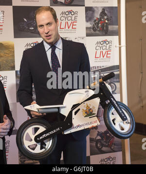 Der Herzog von Cambridge erhält ein Geschenk für seinen Sohn Prinz George vom Ausstellungsleiter Dean Linehan (nicht abgebildet) während seines Besuchs bei Motorcycle Live im NEC, Birmingham. Stockfoto