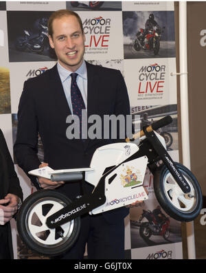 Der Herzog von Cambridge erhält ein Geschenk für seinen Sohn Prinz George vom Ausstellungsleiter Dean Linehan (nicht abgebildet) während seines Besuchs bei Motorcycle Live im NEC, Birmingham. Stockfoto